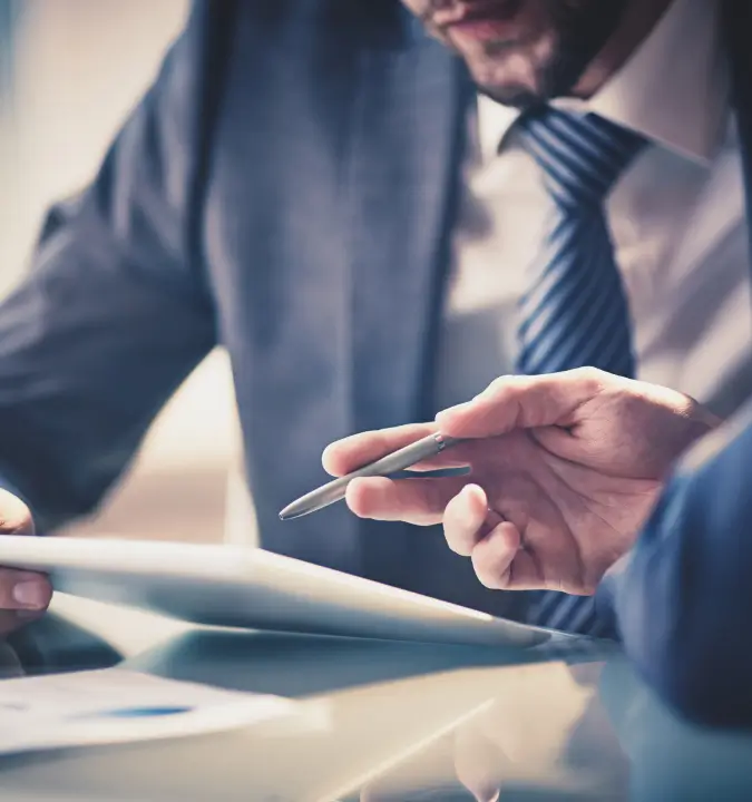 a man in a suit and tie holding a pen and looking at a tablet